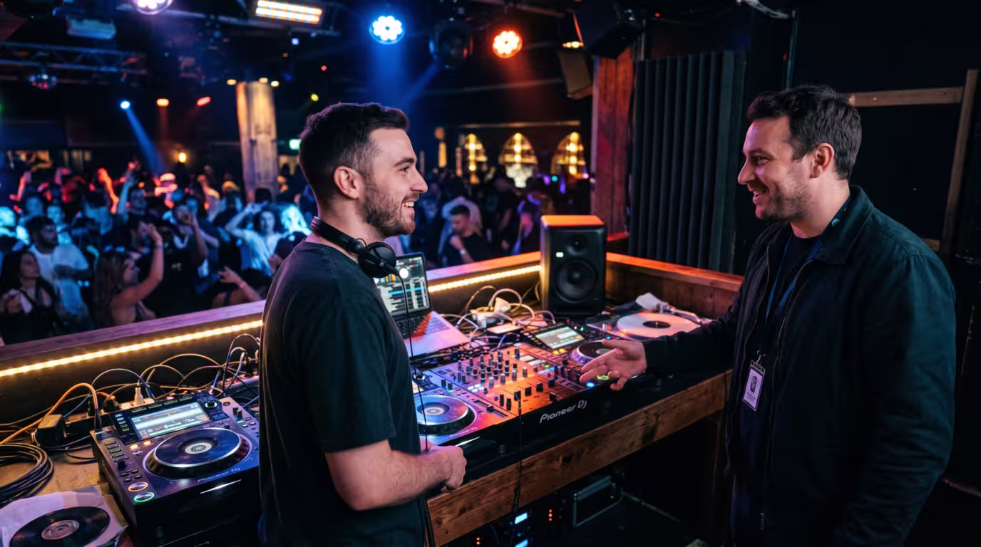 A DJ chatting politely with a venue sound engineer beside the booth