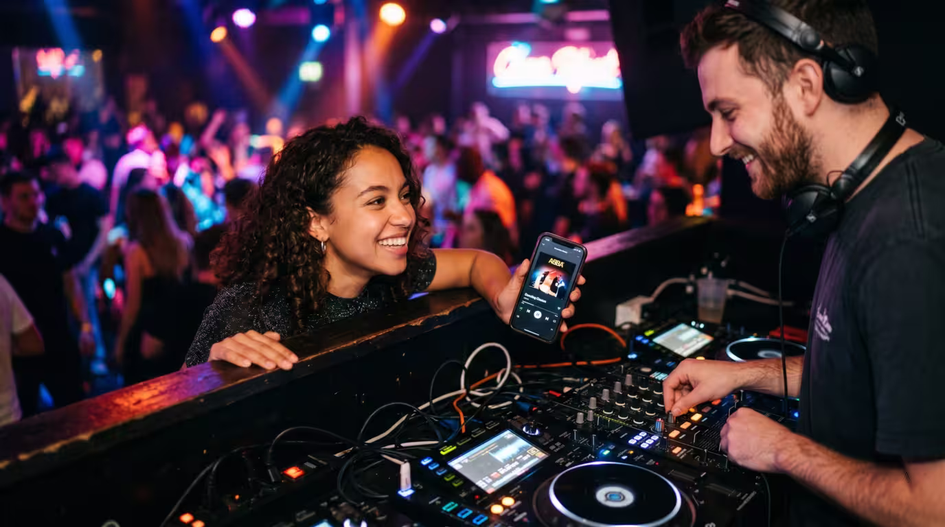 A club-goer leaning over a DJ booth to make a song request