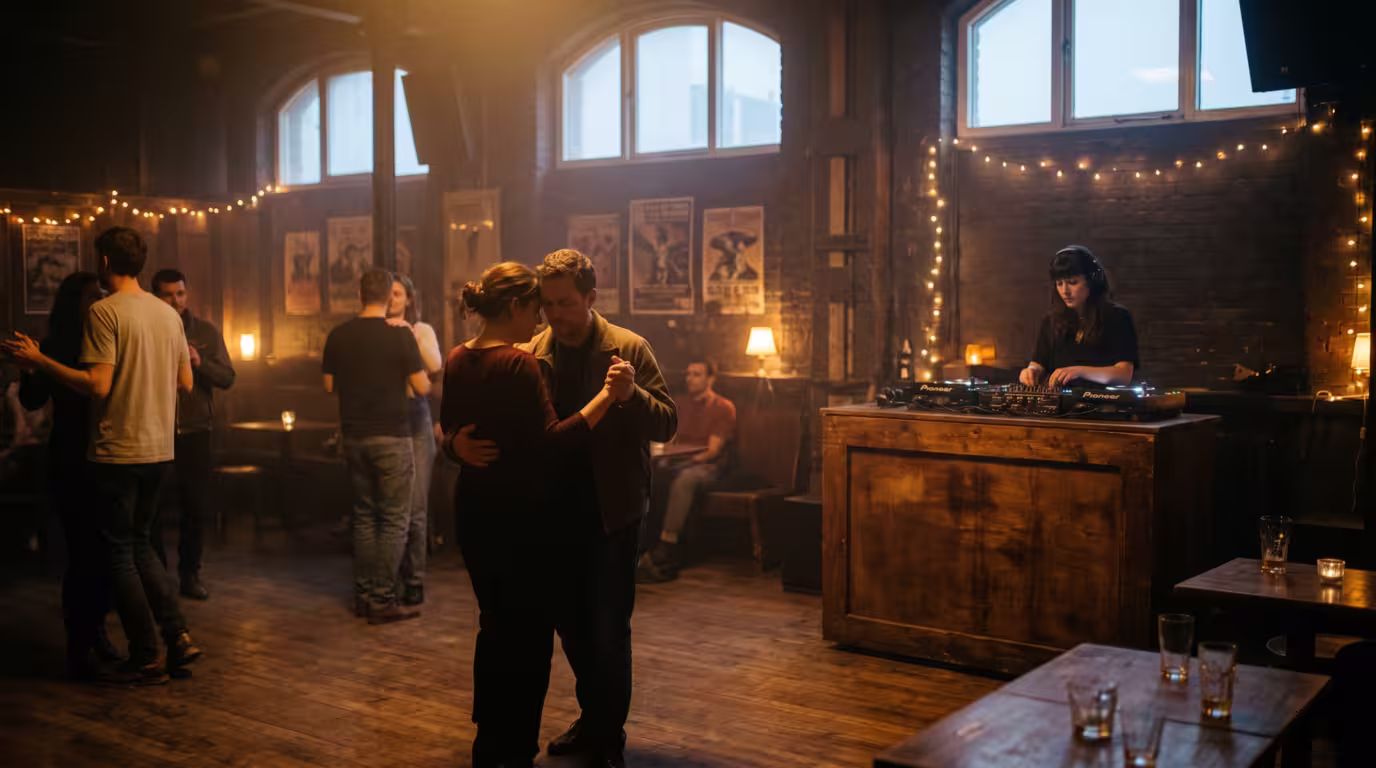 A thinning late-night dance floor with warm dim light and the first hint of dawn