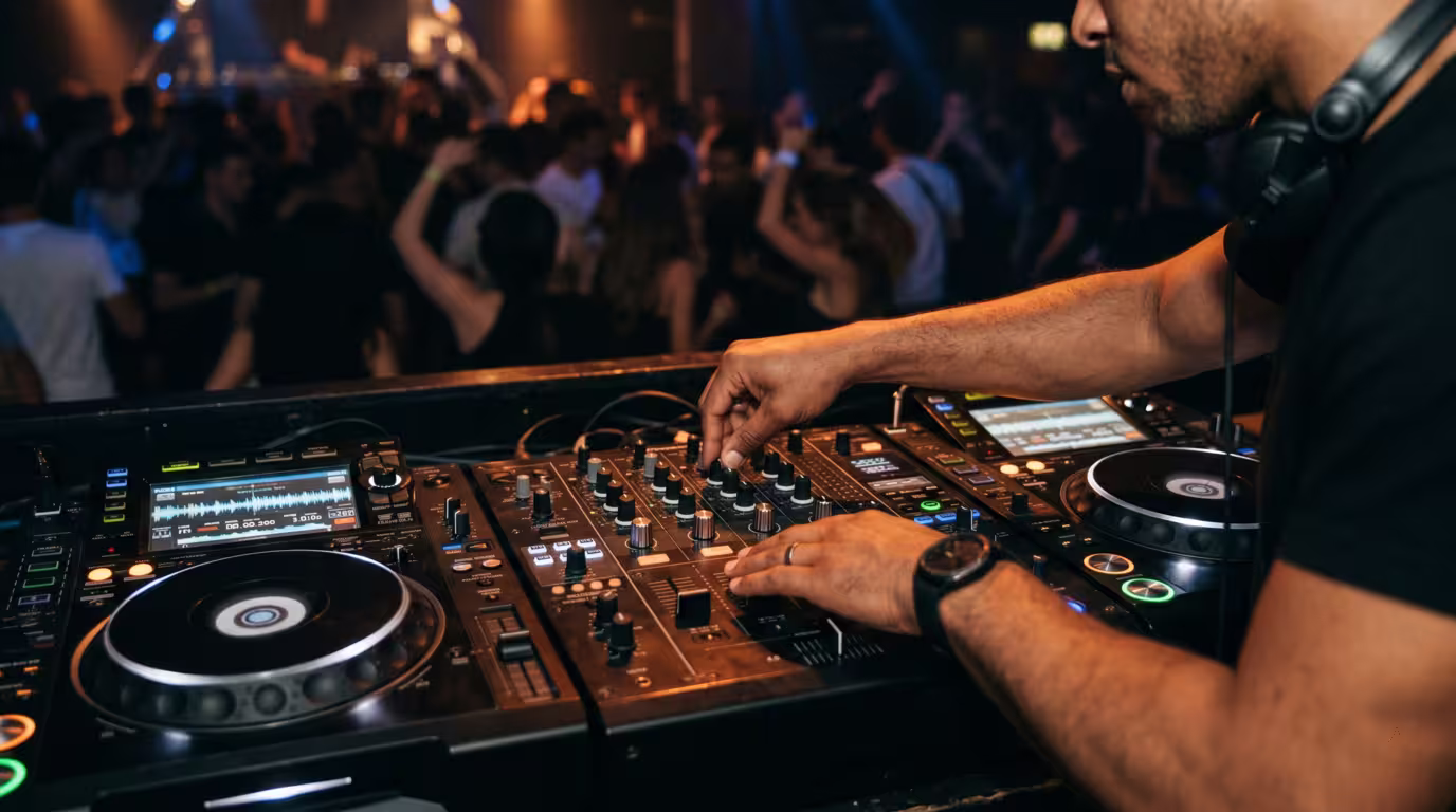 A DJ's hands on a mixer and media players during a set